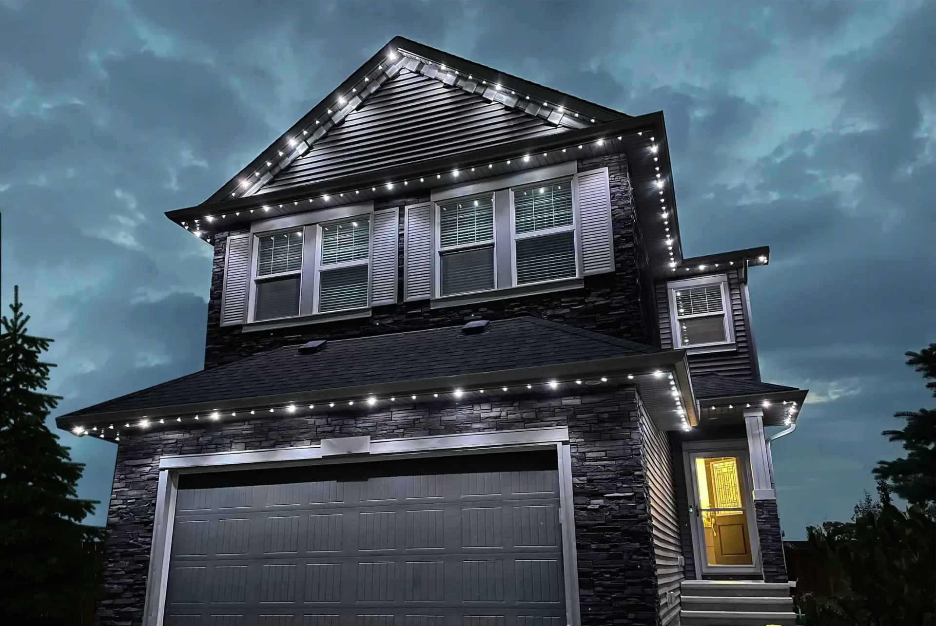 Two-storey home with crisp white permanent roofline lighting at dusk